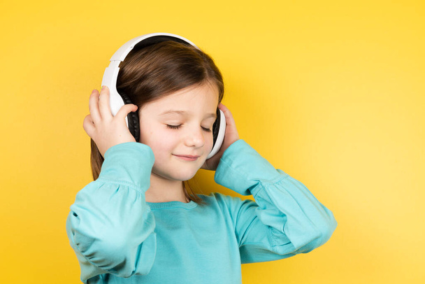 Little girl listening to music on headphones. - Photo, Image