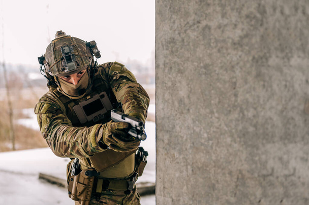 Operador de fuerzas especiales con uniforme Multicam y su pistola xdm 9mm mientras practica entrenamiento de combate CQB en el edificio abandonado. Coyote marrón y mc engranaje con pistola en el entorno urbano. - Foto, Imagen