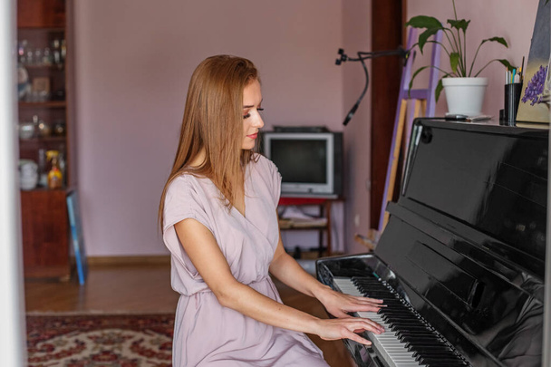 Young woman plays piano at home. Pianist is practicing before concert. Hobies and entertainment. Love classical music. - Foto, imagen