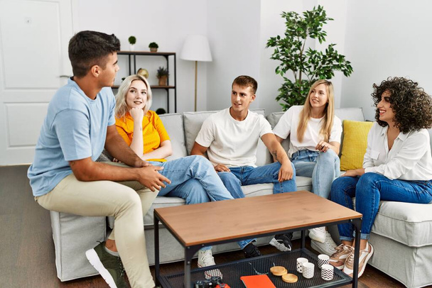 Skupina mladých přátel se šťastně usmívá, když sedí doma na gauči. - Fotografie, Obrázek