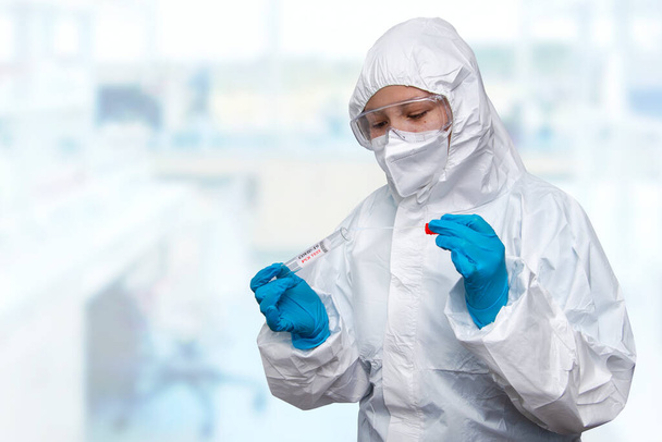 Medical healthcare NHS technician holding COVID-19 swab collection kit,wearing white PPE protective suit mask gloves,test tube for taking OP NP patient specimen sample,PCR DNA testing protocol process - Foto, Imagen
