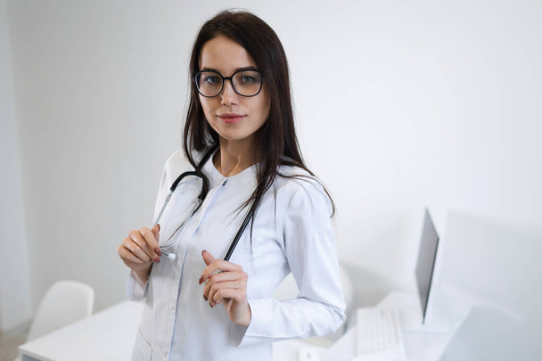 Портрет молодої жінки-лікаря зі стетоскопом, що стоїть в офісі
 - Фото, зображення