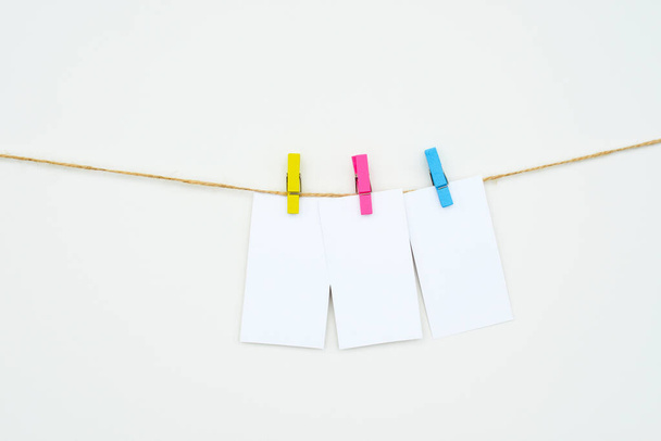 three empty white cards hang on colour clothespins, space for text, tags, word three-letters, mock-up - Foto, afbeelding