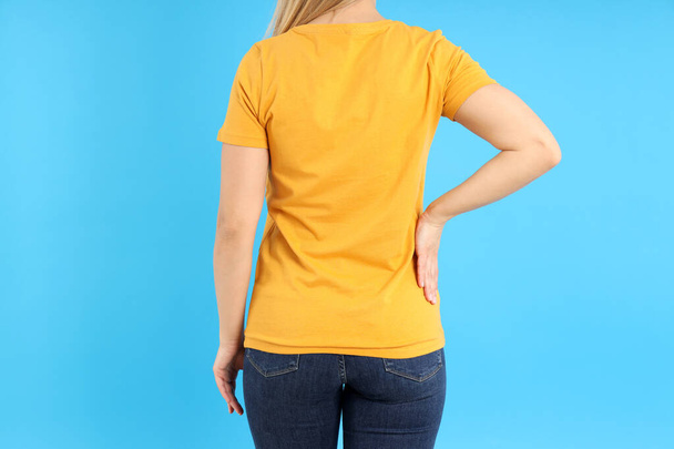 Woman in blank orange t-shirt on blue background - Foto, afbeelding