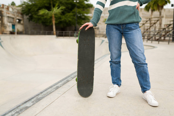 Активна молода жінка тримає скейтборд і готова робити деякі трюки на скейтпарку
 - Фото, зображення