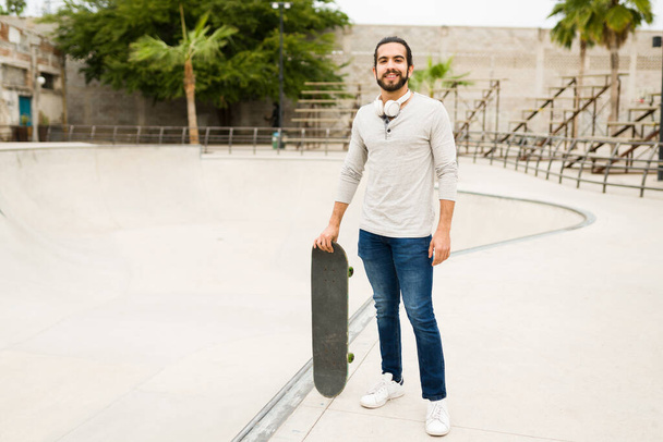 Full length of a happy young man with an active lifestyle using a skateboard at the park - Foto, Imagen