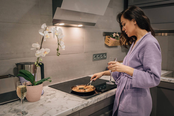 Mladá žena v kuchyni peče palačinky, pečivo na pánvi na sporáku. Životní styl koncepce vaření doma. - Fotografie, Obrázek