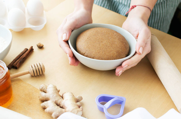 A woman prepares honey - cinnamon cookies. Finished dough in a gray bowl with ingredients around. Family care concept. Horizontal orientation. - 写真・画像