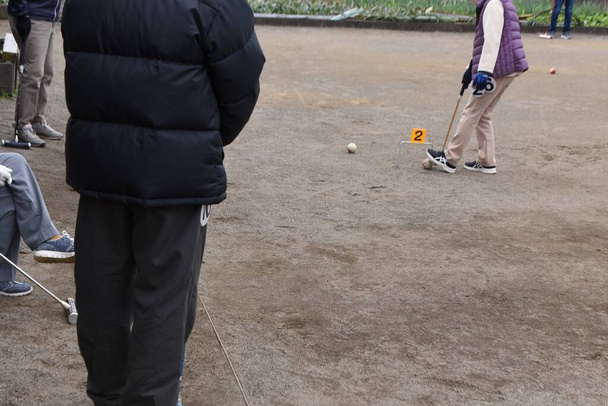 Gateball to sport, który powstał w Japonii i jest bardzo popularny wśród osób starszych. Jest on oparty na krykiecie i jest rozgrywany między dwoma zespołami, z których każda składa się z pięciu członków. - Zdjęcie, obraz