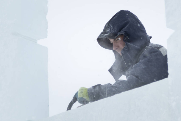 Portrait d'un monteur vêtu d'une veste avec capuche lors de la construction d'un camp de glace
 - Photo, image