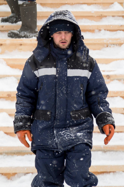 Portrait of an assembler worker in a jacket with a hood at the construction of an ice camp - Photo, Image
