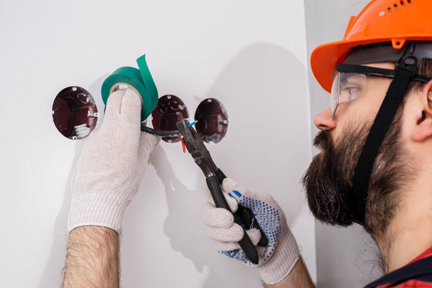 electrician in helmet installs sockets - Photo, Image