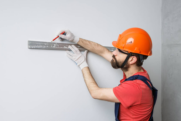oranssikypäräinen työntekijä tarkistaa seinät vedenkorkeudella - Valokuva, kuva