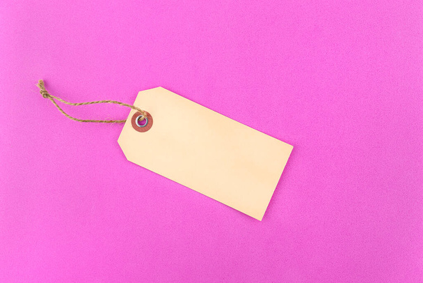 Одна порожня подарункова мітка з ниткою, що лежить на рожевому фоні з губки, в центрі
. - Фото, зображення