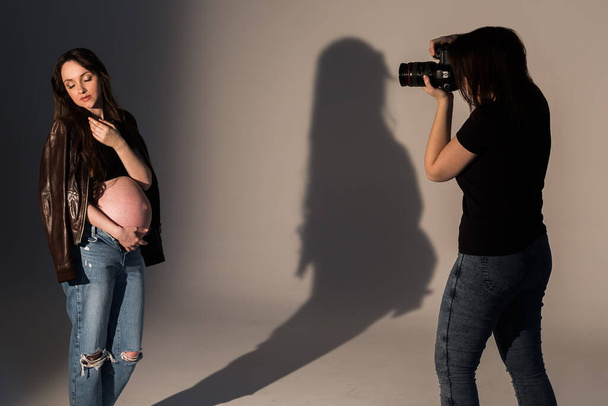 pregnant woman at a photo shoot in the studio, process of photoshooting. Photographer with model - Foto, Bild