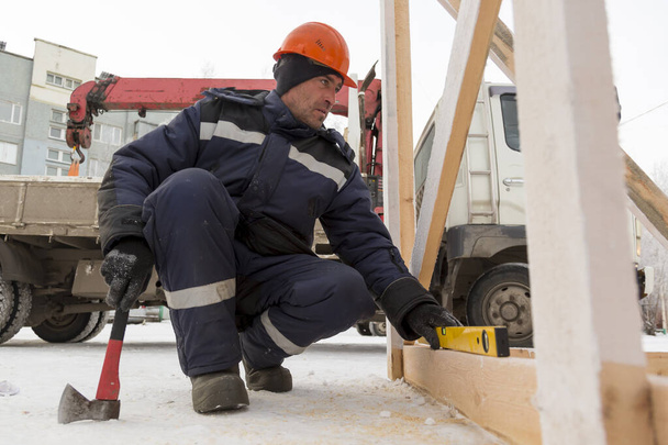 Der Arbeiter legt die Höhe einer Holzstange fest - Foto, Bild