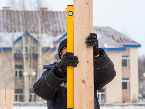 El trabajador establece el nivel de una barra de madera - Foto, imagen