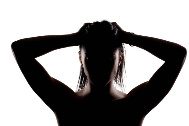 Silhouette portrait of a young brunette girl holding her hair with hands. - Foto, Imagem