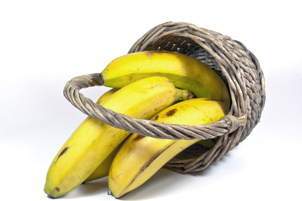 quatro bananas amarelas em uma cesta de vime virada para cima
 - Foto, Imagem