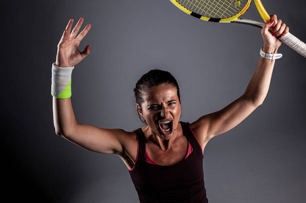 Professional female tennis player. Happy girl screaming with racket in hands. - 写真・画像