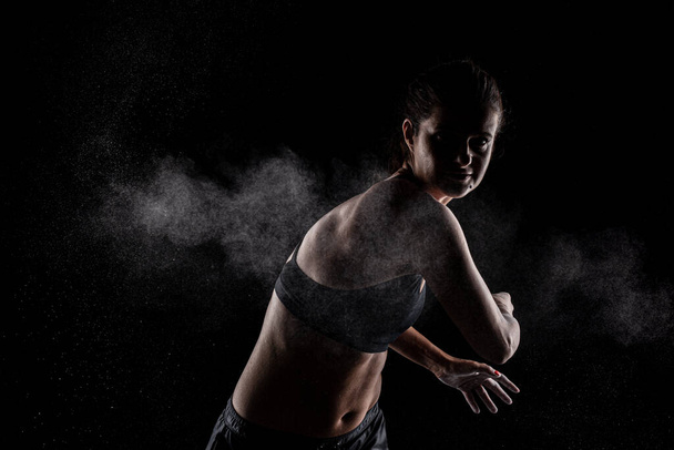 Kickboxer kirl with magnesium powder on her hands, punching with dust visible. - 写真・画像