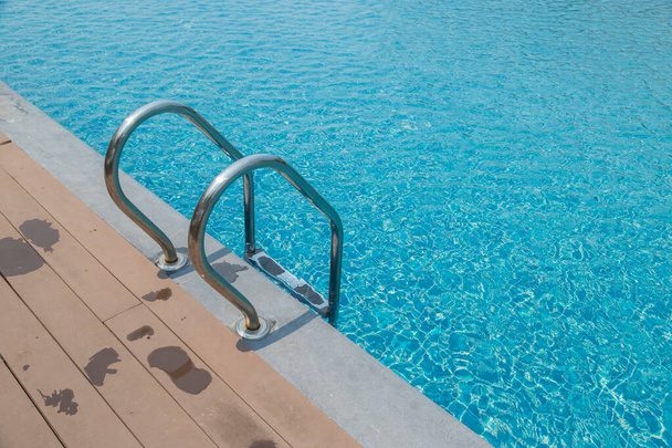 Scale Scala e maniglia giù per la piscina con sfondo blu acqua - Foto, immagini