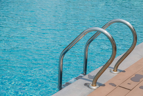 Schody Drabinka i uchwyt w dół basen z niebieskim tle wody - Zdjęcie, obraz