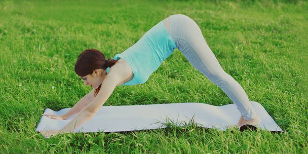 Fitness woman doing exercises on the grass in the summer park - Photo, Image