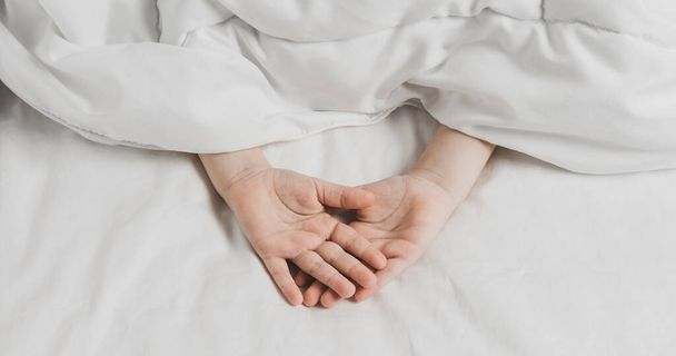 The childs hands are covered with white bed linen. The warmth of home comfort - Photo, Image