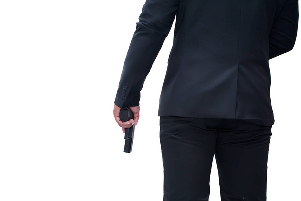 achteraanzicht van wapenman in zwart pak met pistool op witte achtergrond geïsoleerd concept voor moordenaar, moord, crimineel, bandiet. - Foto, afbeelding