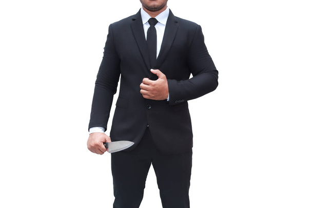 Un homme d'affaires portant un costume noir se tient debout avec un couteau sur un fond blanc isolé.. - Photo, image