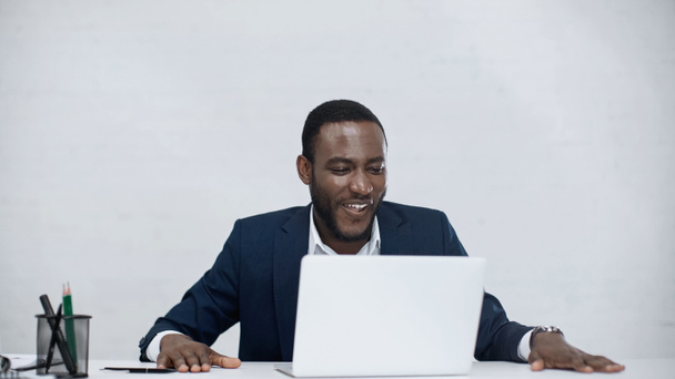 cheerful african american businessman using laptop isolated on grey  - Φωτογραφία, εικόνα