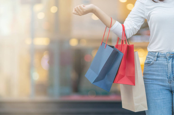 Wazig beeld, jonge vrouw met een boodschappentas na het winkelen voor kortingsartikelen in een warenhuis als de nieuwjaarsvakantie nadert, er is een promotie te koop. winkelconcept - Foto, afbeelding