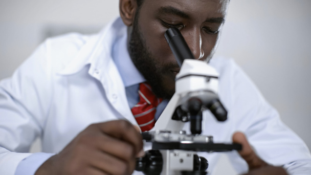african american scientist looking through microscope in laboratory  - Φωτογραφία, εικόνα