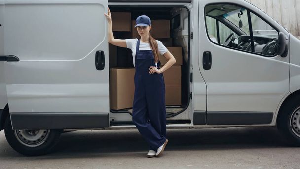 Jeune femme de livraison debout près de boîtes en carton en plein air automatique  - Photo, image