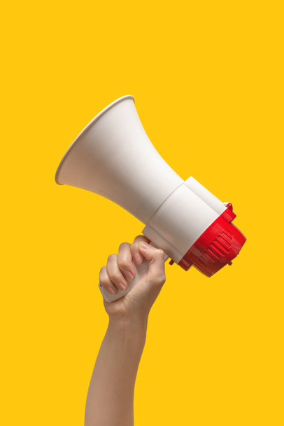 Megaphone in woman hands on a yellow background.  Copy space.  - Photo, Image