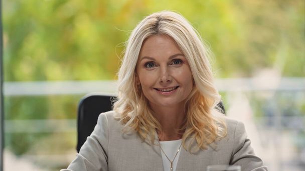 blonde middle aged businesswoman smiling at camera in office - Foto, Imagen