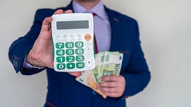 бизнесмен держит евро деньги и калькулятор, бухгалтерский учет или обмен концепции - Фото, изображение
