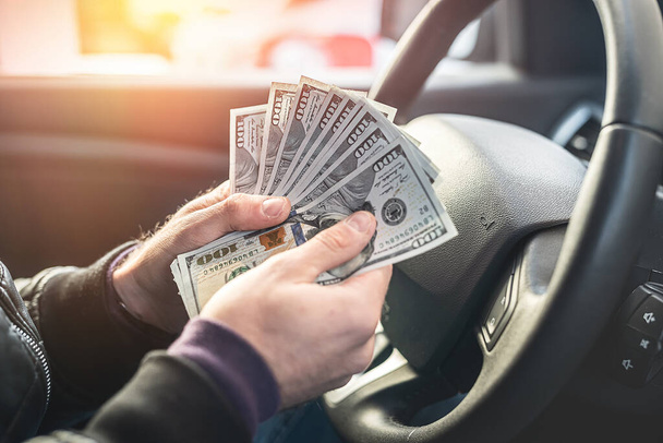 un criminal malo fuerte cuenta una gran cantidad de billetes de dólar dentro de un coche. El concepto de robo y crimen - Foto, imagen