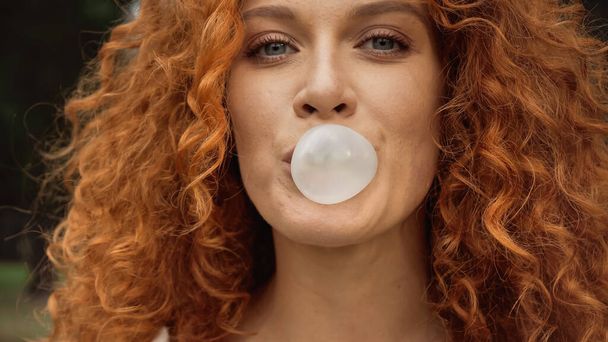 close up view of curly woman blowing bubble gum  - Fotoğraf, Görsel