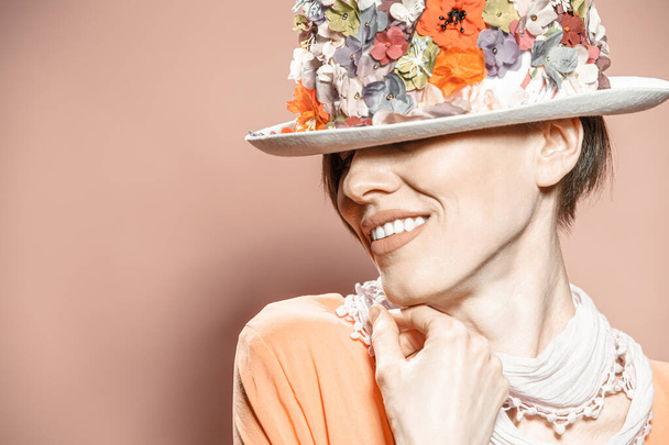 Beautiful woman wearing floral hat over pale brown background - Foto, immagini