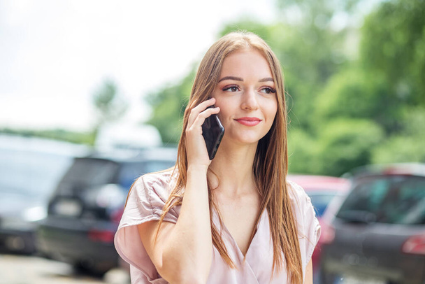 Beautiful light dress in pastel colors. Business woman communicates by smartphone. - Photo, Image