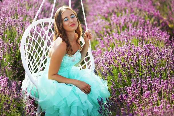 beautiful youn model in turquoise  gown relaxing on lavender field - Fotó, kép