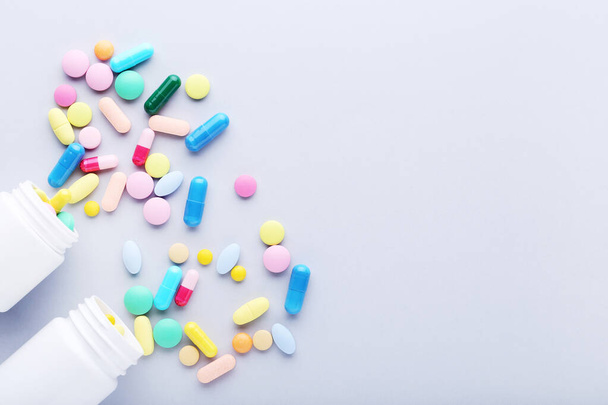 Colorful pills and bottles on grey background - Foto, afbeelding