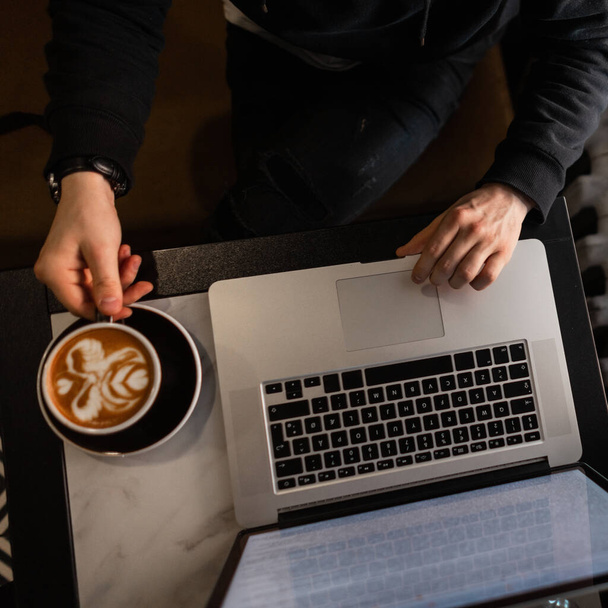 Бизнесмен, работающий за ноутбуком и пьющий кофе, вид сверху - Фото, изображение