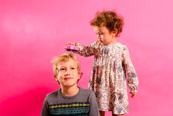 Hermanita ayuda a su hermano mayor a peinarse el pelo, divertida imagen familiar. - Foto, Imagen