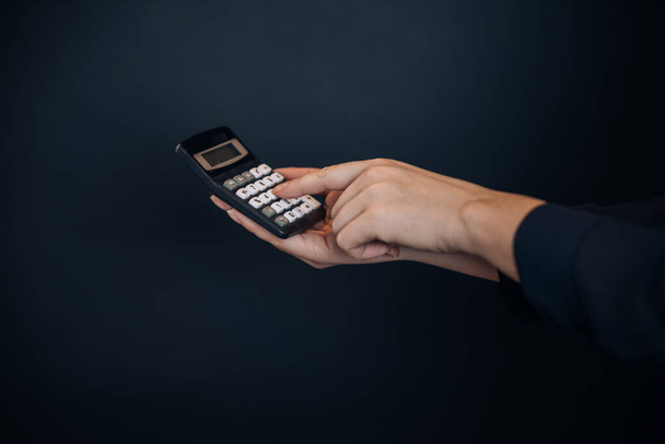 Hand holding calculator on black background - Valokuva, kuva