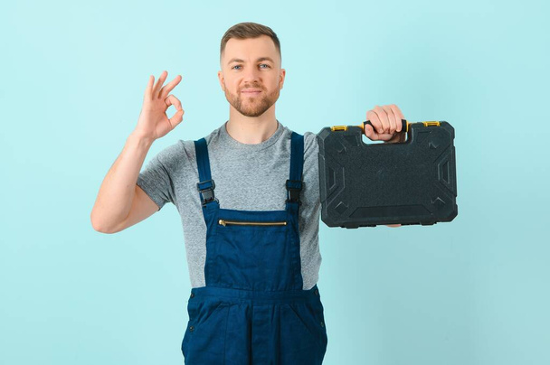 Craftsmen or electrician man over isolated blue background showing an ok sign with fingers - Foto, afbeelding