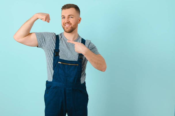 Handsome young craftsman over isolated blue background - Foto, Imagen