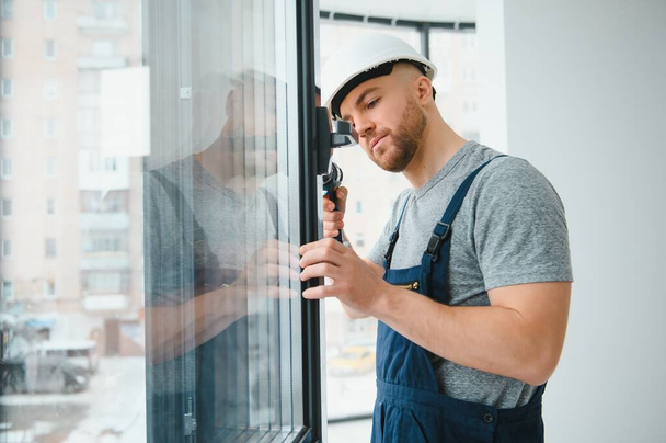 Construction worker repairing plastic window with screwdriver indoors, space for text. Banner design - Фото, изображение